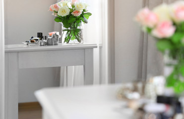 Bouquet of roses on light dressing table reflecting in mirror
