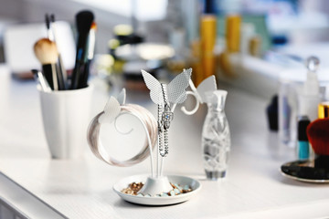 Jewelry holder with cosmetic set on light dressing table