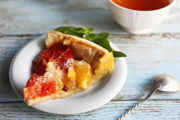 Plate with tasty citrus cake slice on wooden table