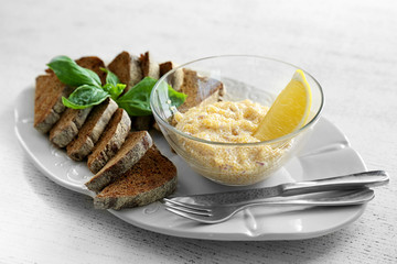 Plate with bread and caviar on wooden table