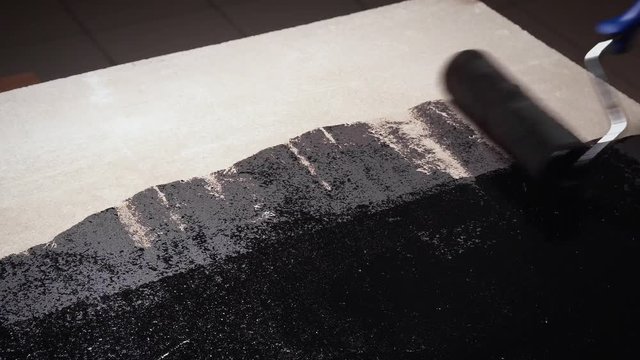 worker with paint roller do covered floors with mastic