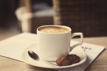 Cup of fresh coffee and morning newspaper on wooden table