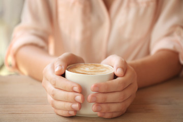 Female hands holding cup of coffee in cafe