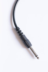 Guitar audio jack with black cable on white background