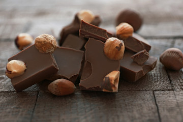 Pile of milk chocolate bars with nuts on old wooden background