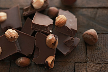 Pile of milk chocolate bars with nuts on old wooden background