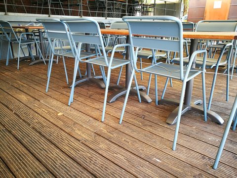 Graue Gartenst&uuml;hle auf stilvollen Schiffsdielen auf der Veranda eines Bistro und Restaurant am Kreativkai an der Hafenpromenade am Hafen von M&uuml;nster in Westfalen im M&uuml;nsterland