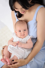 Happy mother playing with her baby girl at home