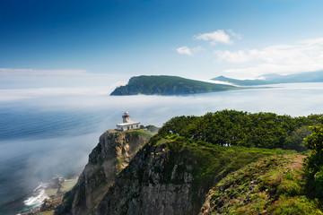 Fototapeta na wymiar Lighthouse on the peninsula Bazeluk Russian Far East. Lighthouse in the fog.