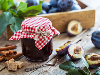 Sweet homemade plum jam and fruits on a wooden table.