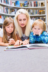 Mother with little girl and boy read book together