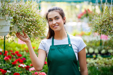 Young beautiful florist posing, smiling among flowers.