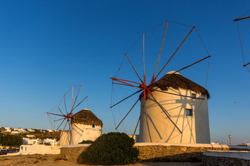 The last rays of the sun over White windmills on the island of Mykonos, Cyclades, Greece
