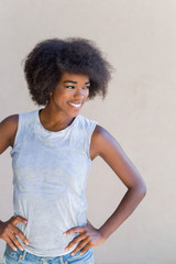 Close up portrait of a young woman smiling with afro hair agains