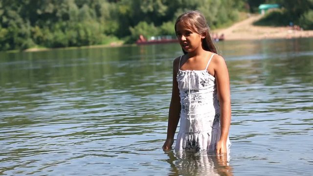 The girl in the dress stands in water