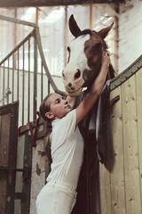 jeune fille 11 ans en tenue d'équitation dans écurie, box avec cheval 