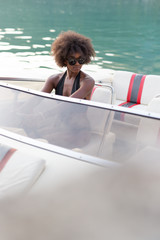 Sexy afro american woman with sunglasses posing on her own yacht