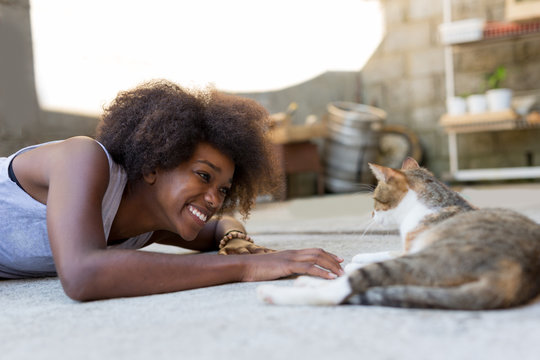 Beautiful afro american woman with her cat on the terrace. Conce