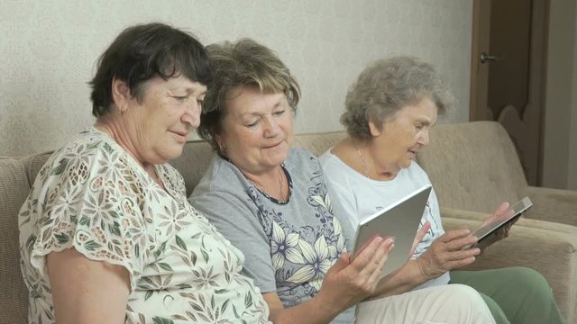 Elderly women look at photos using digital tablets