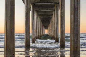 Symmetrischer Schuss unter Scripps Pier mit Wellen bei Sonnenuntergang in La Jolla, San Diego, Kalifornien