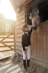 jeune fille 11 ans en tenue d'équitation dans écurie, box avec cheval 