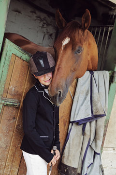 jeune fille 11 ans en tenue d'équitation dans écurie, box avec cheval 