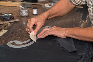 Tailor at work, drawing line on fabric with chalk
