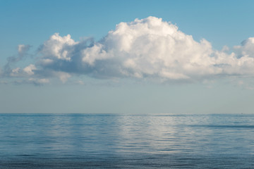 white cloud reflected in calm, still sea on a blue summer's day