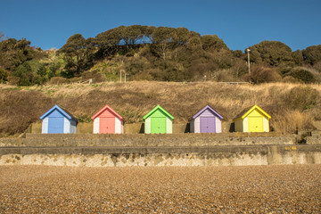 Bright and colourful wooden beach huts on coastal promenade between Folkestone and Sandgate in Kent