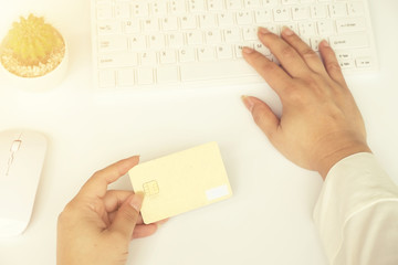Obraz premium Woman's hands holding a credit card and using smart phone for online shopping.vintage tone