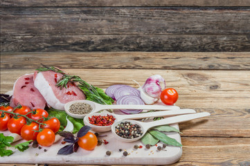 Raw meat, spices and vegetables on rustic wooden board