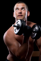 Fototapeta na wymiar pensive bodybuilder while training with dumbbells