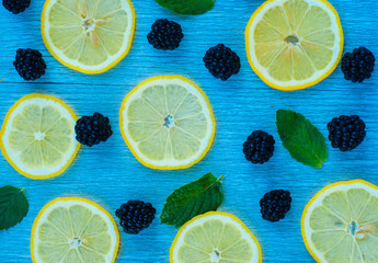 Colorful bright pattern of leaves, blackberries and lemon on blue background