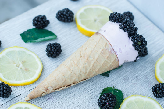 Tasty ice cream with berries in waffle cones on wooden background