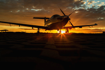 Single turboprop aircraft on runway at sunset time.