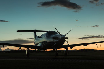 Fototapeta na wymiar Single turboprop aircraft on runway at sunset time.
