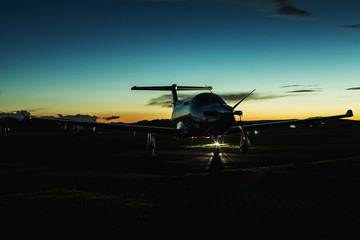 Single turboprop aircraft on runway at sunset time.