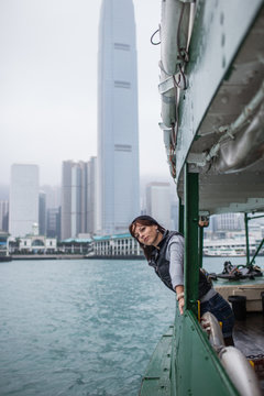 Girl tourist on background of a big city with skyscrapers, looking at the Hong Kong city from the boat