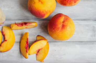 Peaches, whole and slices, on white wooden tabletop