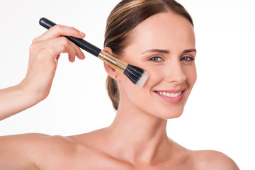 Nice young woman holding makeup brush