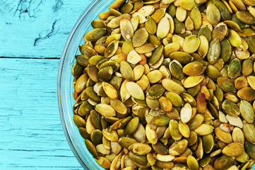 Pumpkin seeds on the plate on a wooden background