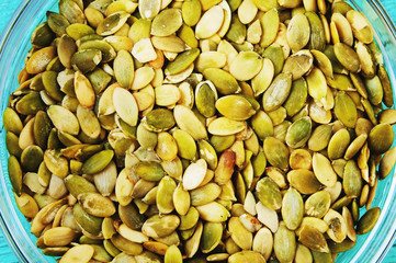 Pumpkin seeds on the plate on wooden background