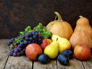 Obraz na płótnie Canvas still life of autumn fruits: pumpkin, grape, apple, pear, plum on a wooden background. selective focus