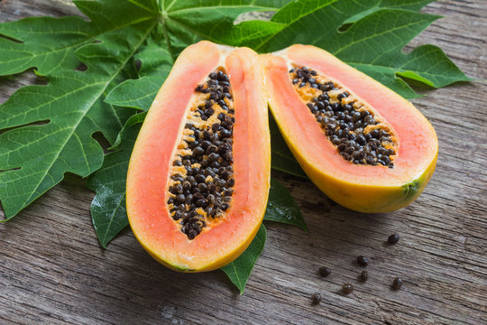 Ripe papaya with green leaf on wooden background