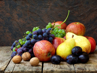 still life of autumn fruits: grapes, apples, pears, plums, nuts on a wooden background. selective focus