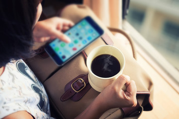 Young girl holding coffee cup and smartphone.