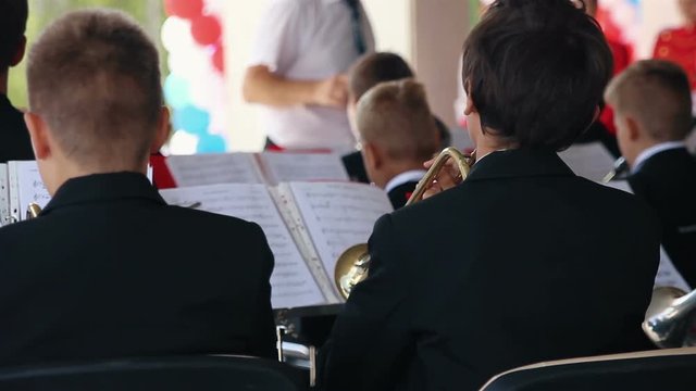 Young guys play on wind instrument in orchestra