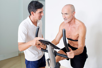 Elderly senior with coach on indoor bike