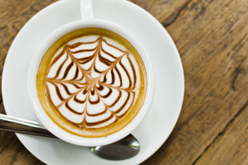 Coffee cup on the wood texture background, selective focus on coffee cream.