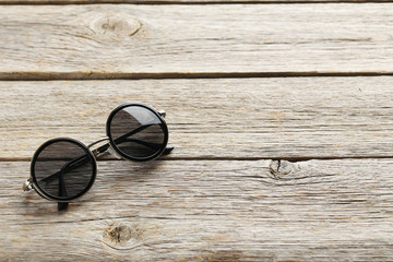Fototapeta na wymiar Black sunglasses on a grey wooden table